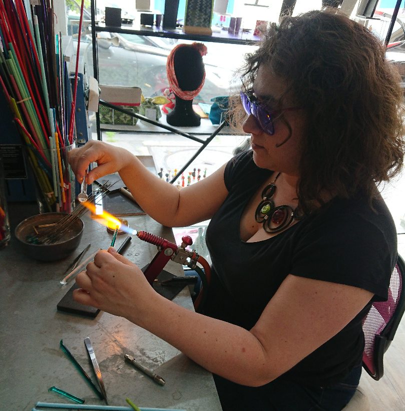 Nathalie créatrice des bijoux en verre Diatomée travaille au chalumeau dans son atelier boutique parisien
