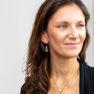 Une photo portée avec les boucles d'oreilles en verre de Murano transparentes incolores faites à la main par la créatrice Diatomée dans son atelier boutique à Paris 14